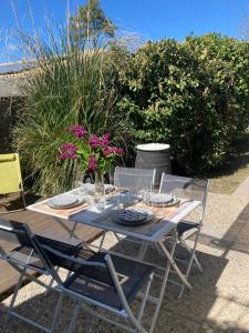 a table with plates and glasses and flowers on it at Studio avec grande terrasse et jardin privatif au Pyla in La Teste-de-Buch