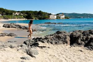 une femme en bikini marchant sur une plage dans l'établissement Azzura, duplex lumineux accès direct à la plage, à Sainte-Maxime