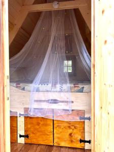 uma cama num chalé de madeira com uma rede mosquiteira em Märchenhütte- Campen am Wald und See em Neuruppin