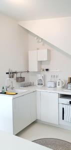 una cocina blanca con armarios y electrodomésticos blancos en loft 85 m2 Wilanow Krolewski self checkin, en Varsovia