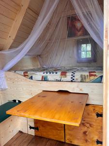a wooden table in a cabin with a bed at Märchenhütte- Campen am Wald und See in Neuruppin