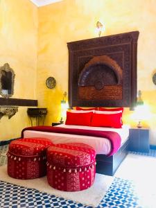 ein Schlafzimmer mit einem Bett mit roten Kissen und zwei roten Ottomanen in der Unterkunft Riad Safari Fes in Fès