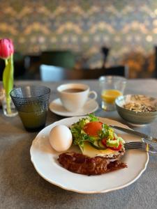 a plate of food on a table with eggs and bacon at Eleonora Bed & Breakfast in Kristinestad