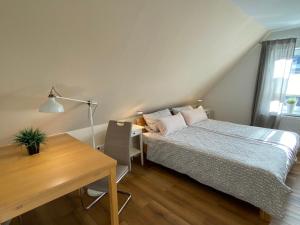 een slaapkamer met een bed, een bureau en een tafel bij Ferienwohnung Ausguck in Jever