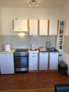 una cucina con armadi bianchi e piano cottura di S-Lux apartman a Sombor
