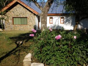 een huis met een bos met roze bloemen ervoor bij White Field Houses and Spa in Villa Las Rosas