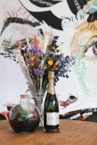 een fles wijn en een vaas met bloemen op een tafel bij Beachhouse Renesse 2645 in Renesse