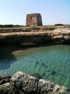 un edificio en una colina junto a un cuerpo de agua en Masseria Boezio Ostuni, en Torre Santa Sabina