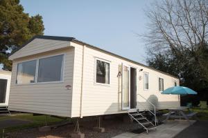 a white tiny house with a table and an umbrella at 41 Orchard Bank, 3 bed, Rockley Park Poole in Poole