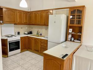 uma cozinha com armários de madeira e um frigorífico branco em Aegean Breeze Beach House em Artemida