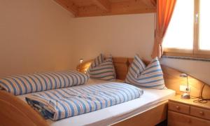 uma cama com almofadas azuis e brancas e uma janela em Ferienwohnungen Kaltenbachhof - Urlaub auf dem Biobauernhof em Parcines