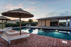 a swimming pool with two chairs and an umbrella at Villa Nicoletta in Santa Teresa Gallura