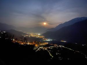 a view of a city at night with the moon at B&B Monte Tesobo in Roncegno +42 photos