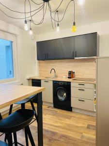 een keuken met een tafel en een wasmachine bij Appartement 2 chambres avec terrasse vue sur jardin arboré in Pontarlier