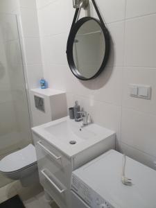 a white bathroom with a sink and a mirror at Good Time Apartaments Sienkiewicza in Leszno