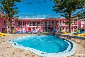 a pink house with a swimming pool in front of it at Pink Palace Beach Resort in Agios Gordios