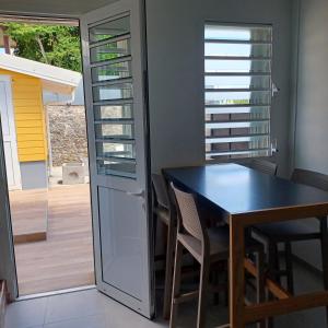 una sala da pranzo con tavolo e sedie accanto a una porta di Maison de vacances les pieds dans l'eau a Schœlcher