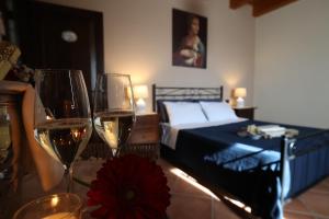a bedroom with a bed and two glasses of wine at La Cascina Nel Bosco in Faicchio
