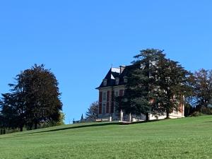 a large house on top of a grassy hill at Domaine de Mont-Renaud in Boncourt