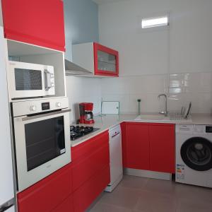 une cuisine avec des armoires rouges et un appareil blanc dans l'établissement Maison de vacances les pieds dans l'eau, à Schœlcher