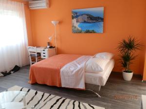 a bedroom with orange walls and a bed and a desk at Apartment RINO****, 58m², 170m from the beach in Rijeka