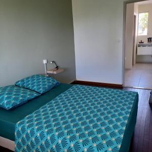 um quarto com uma cama com um edredão azul em Maison de vacances les pieds dans l'eau em Schœlcher