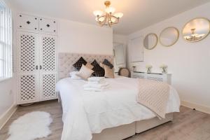 a white bedroom with a large white bed and mirrors at Gloucester Place Townhouse with Hot Tub! in Cheltenham