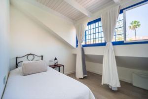 1 dormitorio con cama blanca y ventana en FABULOUS BUNGALOW , WIFI, SWIMMING POOL AND BEACH en Pasito Blanco