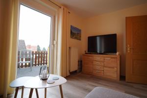 a living room with a television on a dresser with a table at Auszeit - Ferienwohnung und Appartements in Bad Sooden-Allendorf