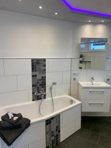 ein weißes Badezimmer mit einer Badewanne und einem Waschbecken in der Unterkunft Schleibungalow Nr15 zw Ostsee und Schlei in Kappeln