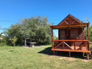 una pequeña casa de madera en un campo con un banco en Chacra Mandala en Gualeguay