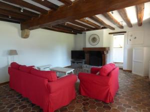 a living room with two red chairs and a fireplace at la pause campagne in Pullay