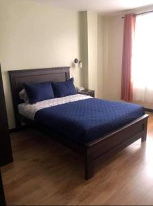 1 dormitorio con cama con sábanas azules y ventana en HOTEL CENTRAL en El Tambo