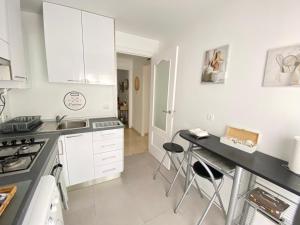 cocina con armarios blancos y encimera negra en Apartamento Plaza España Las Rozas en Las Rozas de Madrid