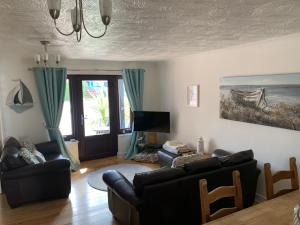 a living room with two couches and a tv at Ivory Lane in Trearddur