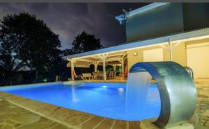 a pool with a water slide in front of a house at Appartement d'une chambre avec vue sur la ville piscine partagee et terrasse amenagee a Fort de France a 4 km de la plage in Fort-de-France