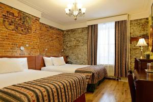 um quarto de hotel com duas camas e uma parede de tijolos em Hôtel Manoir de l'Esplanade em Cidade de Quebec