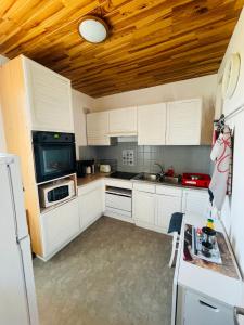 cocina con armarios blancos y techo de madera en Studio COSY avec parking et wifi gratuit, en Bagnoles de l'Orne