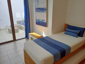 a bedroom with a bed with blue pillows and a balcony at Apartamento (Cotillo Mar) con vistas al Mar in Cotillo