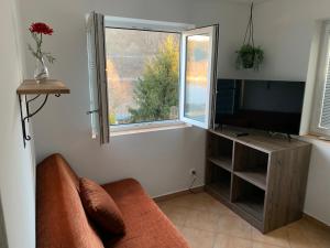 - un salon avec un canapé, une télévision et une fenêtre dans l'établissement Chata Omicron, à Bítov