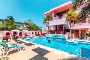 a swimming pool in front of a pink building at Miramar Suites in Placencia Village