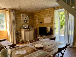 a living room with a table and a television at Domaine le Manoir, gîtes de charme et de caractère avec piscines privatisées et spa nordique in Fossemagne