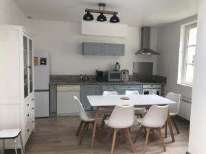 a kitchen with a white table and white chairs at La Tranquillité proche Beauval et Châteaux de la Loire in Loches