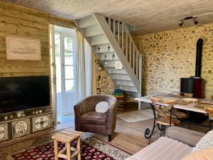 a living room with a tv and a staircase at Domaine le Manoir, gîtes de charme et de caractère avec piscines privatisées et spa nordique in Fossemagne