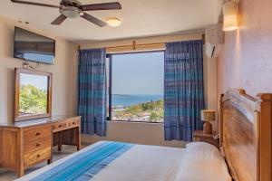 a bedroom with a bed and a large window at Hotel El Mirador in Puerto Escondido