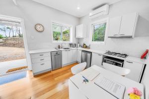 a kitchen with white cabinets and a table and chairs at Cromwell Lite in Cooma