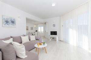 ein weißes Wohnzimmer mit einem Sofa und einem Tisch in der Unterkunft Guest house LUCIJA with swimming pool in Tugare