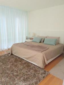 a large bed in a white bedroom with a rug at Ocean Village 10 in Grândola