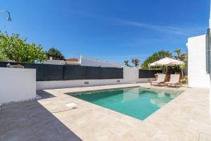 a swimming pool with two chairs and an umbrella at Villa Mica in Son Carrio