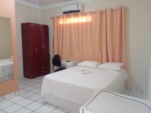 ein Schlafzimmer mit einem Bett und ein Badezimmer mit einem Waschbecken in der Unterkunft Pousada Terra do Sol in Caicó